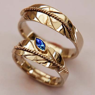 'Opdat Onze Levens Oprecht Mogen Zijn': bicolor gouden arendsveer ringen waarvan de damesring is gezet met een blauwe saffier